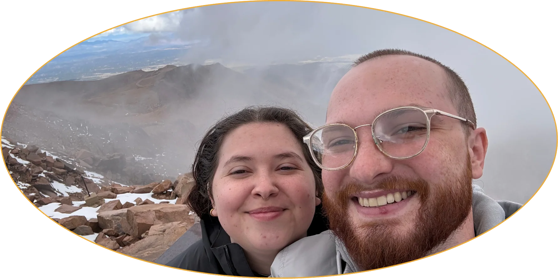 Rae and Chandler smiling on a misty mountain top